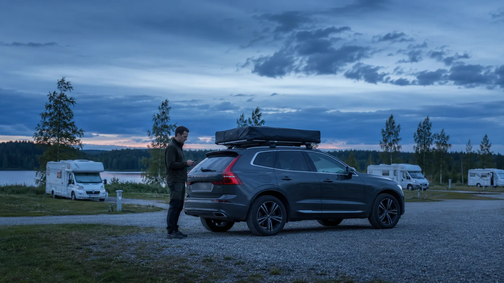 A Volvo XC60 with a closed rooftop tent at a Swedish motorhome stopover in blue evening light