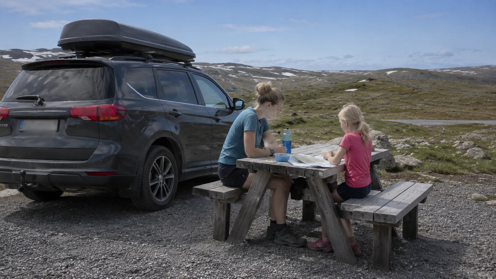 An adult and child having fika beside the car on Nipfjället