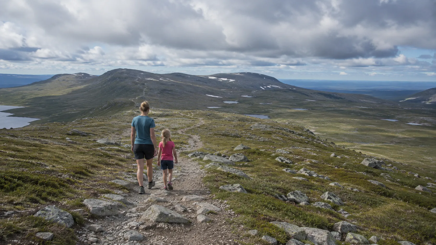 An adult and child walking a rocky mountain path